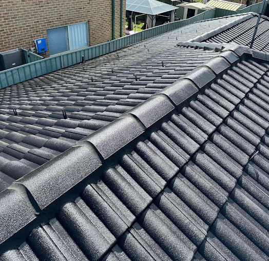 A close-up view of a gray-tiled roof with a clear sky background, highlighting the neatly arranged tiles and roof ridge.