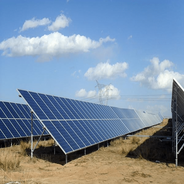 Rows of solar panels installed on a sandy ground under a blue sky with scattered clouds.