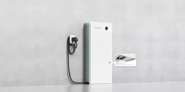 Wall-mounted electric vehicle charging station with cord and plug, set against a concrete wall. Includes an inset image showing close-up of a charging port.