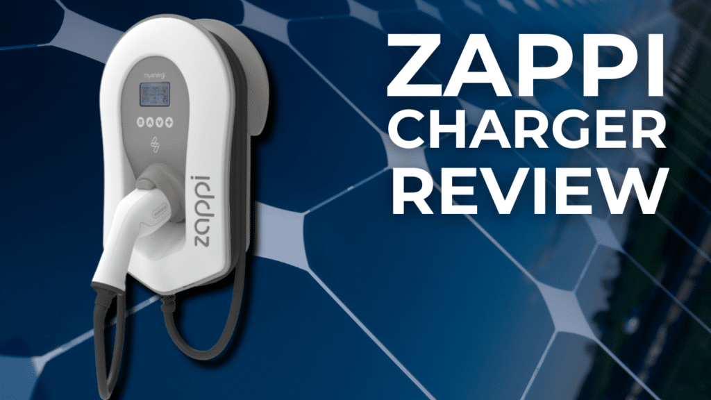 A Zappi electric car charger is mounted on a wall with the text "Zappi Charger Review" beside it, set against a background featuring a close-up of solar panels.